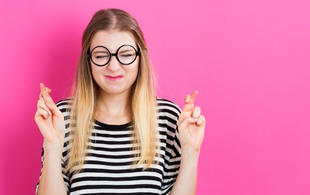 Young woman crossing her fingers and wishing for good luck